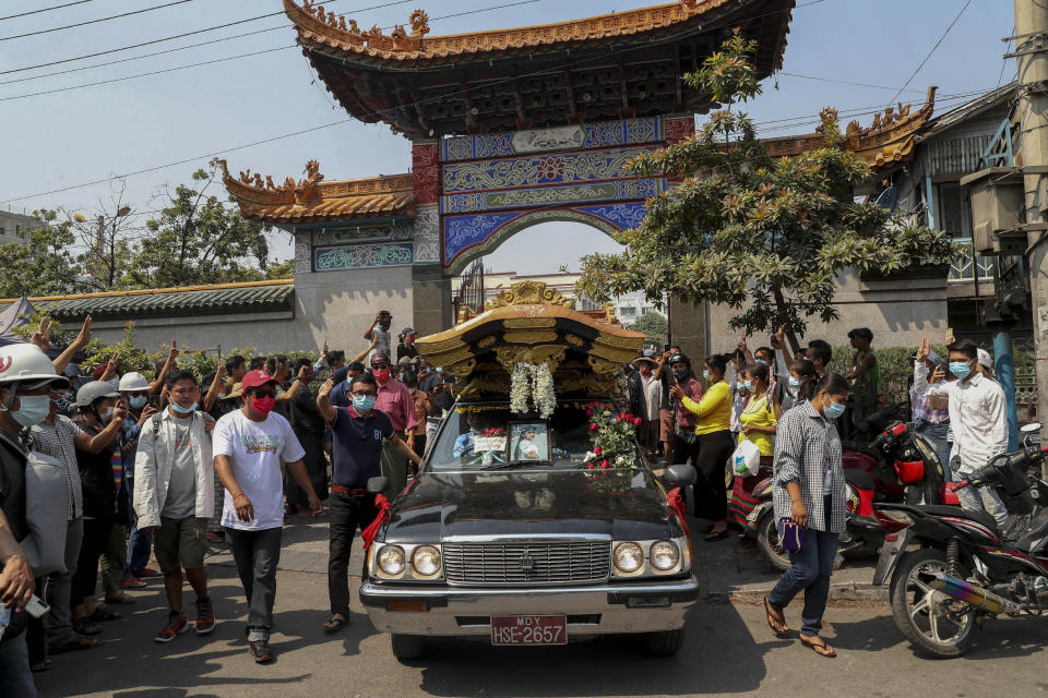 In this March 4, 2021, file photo, bystanders flash a three-fingered sign of resistance as the body of anti-coup protester Kyal Sin, also known by her Chinese name Deng Jia Xi, leaves the Yunnan Chinese temple in Mandalay, Myanmar. Kyal Sin was shot in the head by security forces during an anti-coup protest rally she was attending Wednesday. (AP Photo, File)