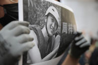 A protester holds up a photo of Chow Tsz-Lok as they disrupt a graduation ceremony at the University of Science and Technology in Hong Kong on Friday, Nov. 8, 2019. The ceremony was cut short, and black-clad masked students turned the stage into a memorial for Chow who fell off a parking garage after police fired tear gas during clashes with anti-government protesters and died Friday. (AP Photo/Kin Cheung)