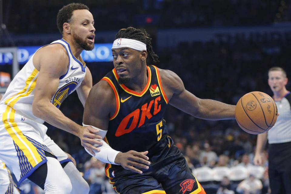 Oklahoma City Thunder guard Luguentz Dort (5) dribbles the ball as Golden State Warriors guard Stephen Curry defends during the first half of an NBA in-season tournament basketball game Friday, Nov. 3, 2023, in Oklahoma City. (AP Photo/Nate Billings)