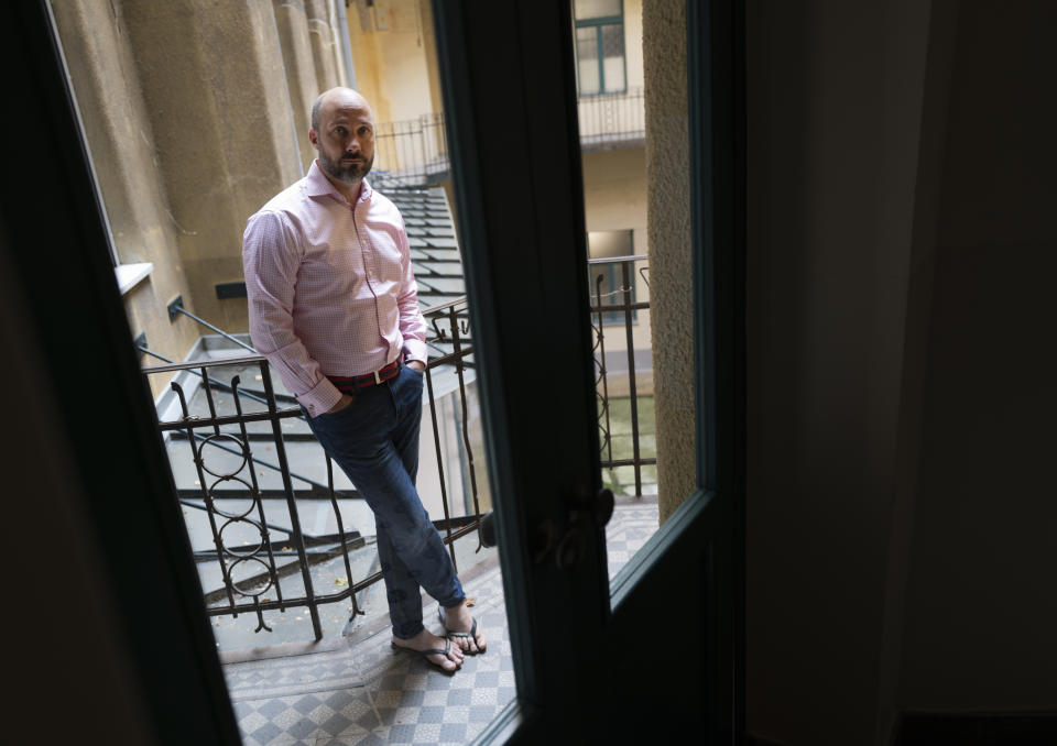 Novelist Mark Mezei poses for a photo in his home in Budapest, Tuesday, July 13, 2021. A recent Hungarian law that prohibits “depicting or promoting” homosexuality or sex reassignment to minors has some bookstores in Hungary placing notices at their entrances, warning customers over books containing “non-traditional content.” Some writers and publishers say the controversial law narrows free thought and expression in literature - and are uncertain over whether works that depict homosexual themes will require labeling to keep them from reaching minors under 18. (AP Photo/Bela Szandelszky)