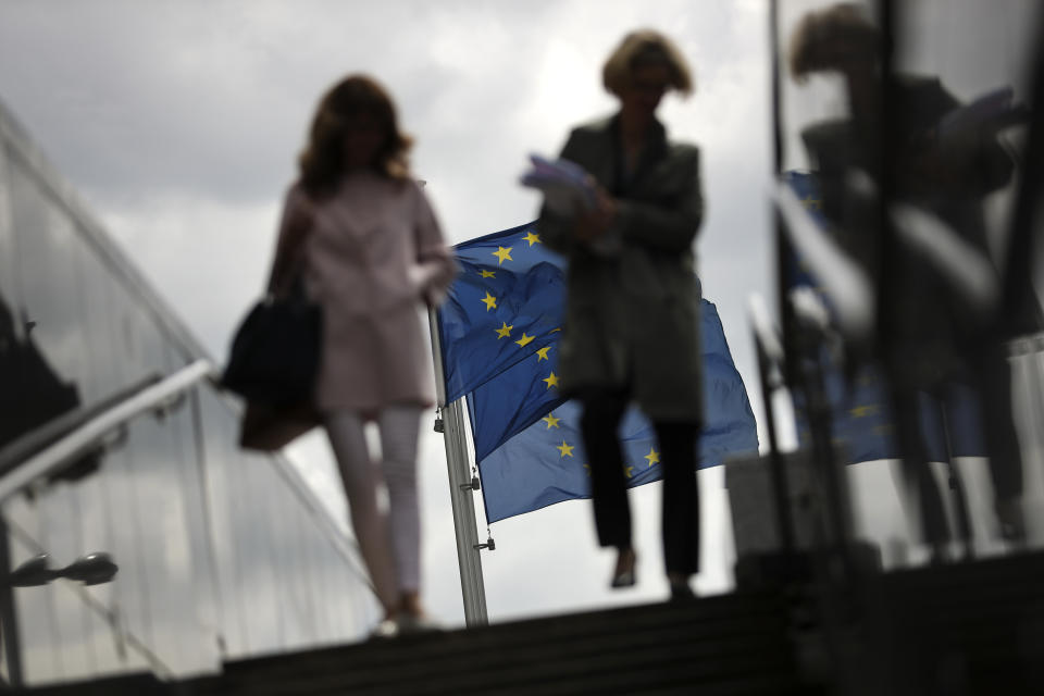 Two women walk near EU flags outside the European Commission headquarters in Brussels, Monday, May 27, 2019. Europeans woke Monday to a new political reality after European Parliament elections ended the domination of the EU's main center-right and center-left parties and revealed a changed political landscape where the far-right, pro-business groups and environmentalists will be forces to be reckoned with. (AP Photo/Francisco Seco)