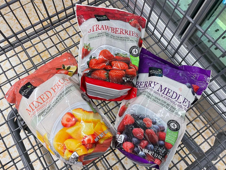 Three bags of frozen fruit in a cart: mixed fruit, strawberries, and berry medley.