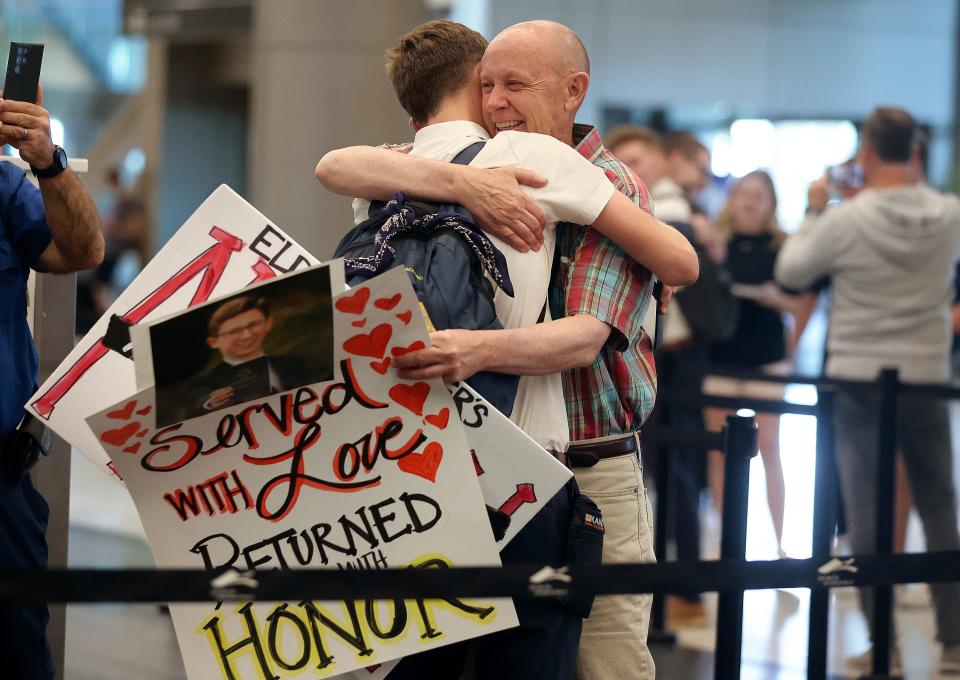 Darren Tanner, right, holds signs as he hugs his son, Elder Simon Tanner, arriving home from serving a mission on the Ivory Coast, at the Salt Lake City International Airport in Salt Lake City on Tuesday, June 20, 2023. | Kristin Murphy, Deseret News