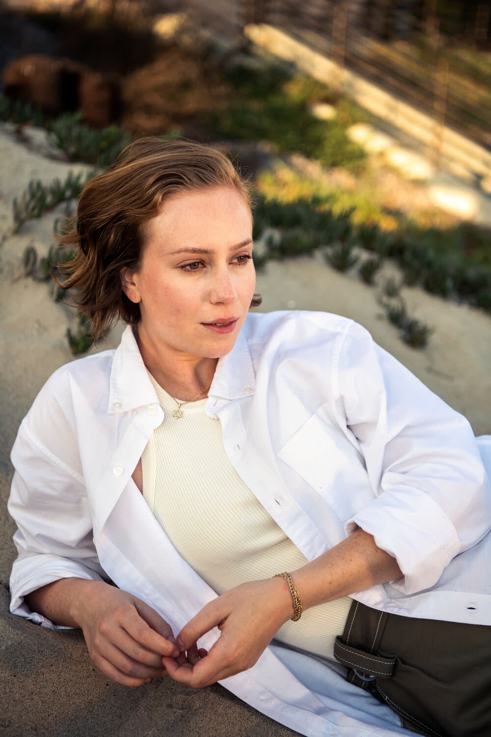 A woman lies down on the beach and looks off into the distance