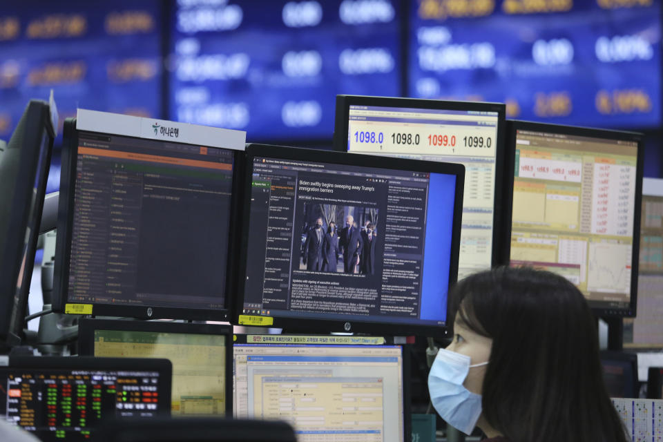 A screen shows a news report about U.S. President Joe Biden's inauguration as a currency trader works at the foreign exchange dealing room of the KEB Hana Bank headquarters in Seoul, South Korea, Thursday, Jan. 21, 2021. (AP Photo/Ahn Young-joon)