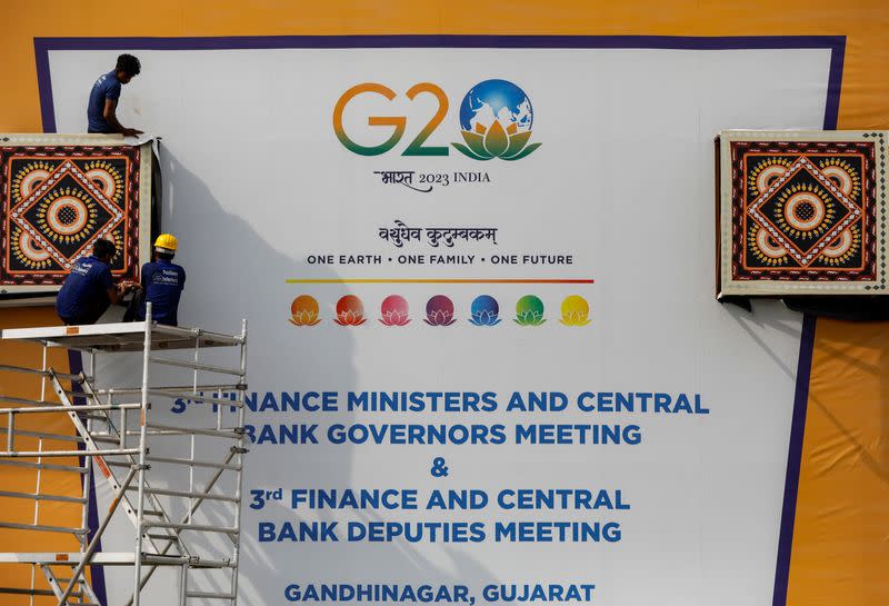 Workers work to install a hoarding board near the venue of G20 Finance Ministers and Central Bank Governors meeting at Gandhinagar in Gujarat