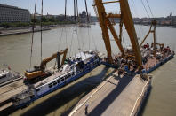 FILE - In this Tuesday, June 11, 2019, file photo, a crane lifts the sightseeing boat out of the Danube river in Budapest, Hungary. Preparations are underway for commemorations to be held on the first anniversary of the May 29, 2019, mishap on the Danube River in which a sightseeing boat carrying mostly tourists from South Korea sank after a collision with a river cruise ship. Just seven of the 33 South Korean tourists aboard the Hableany (Mermaid) survived the nighttime collision at Budapest's Margit Bridge. (AP Photo/Darko Bandic, File)