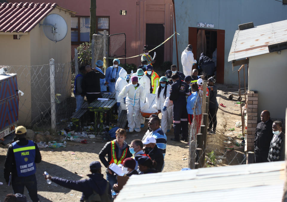 Forensic personel carry a body out of a township pub in South Africa's southern city of East London on June 26, 2022, after 20 teenagers died.