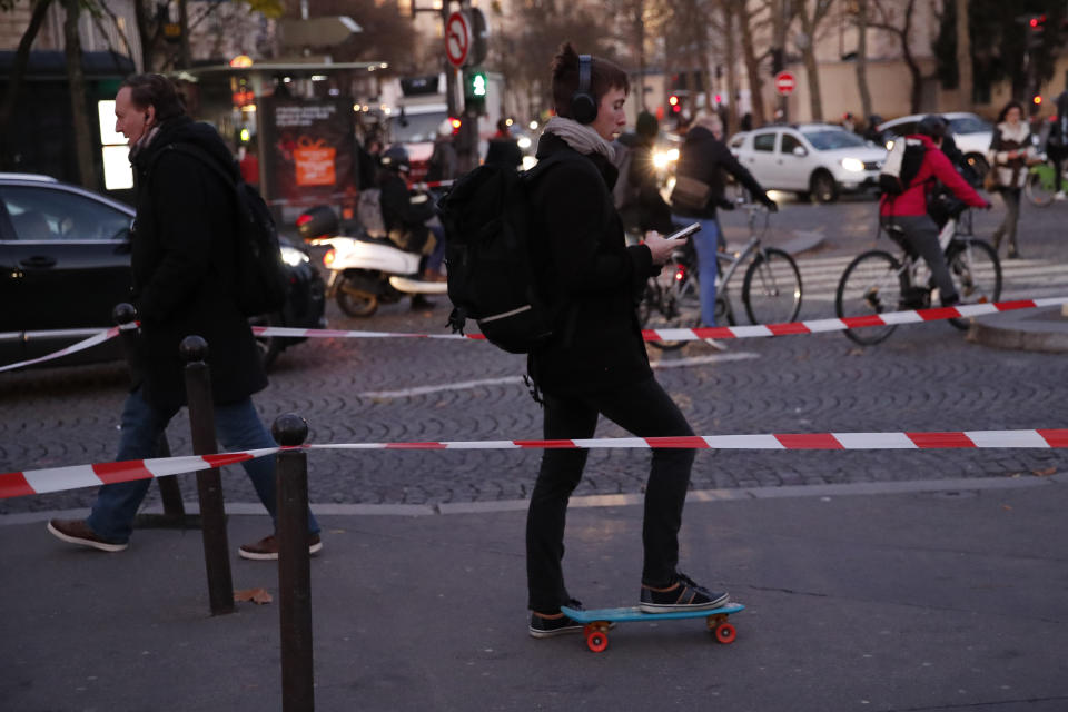 Parisians walk, ride bicycles or a skate board Tuesday, Dec. 10, 2019 in Paris. Only about a fifth of French trains ran normally Tuesday, frustrating tourists finding empty train stations, and most Paris subways were at a halt. French airport workers, teachers and others joined nationwide strikes Tuesday as unions cranked up pressure on the government to scrap changes to the national retirement system. (AP Photo/Francois Mori)
