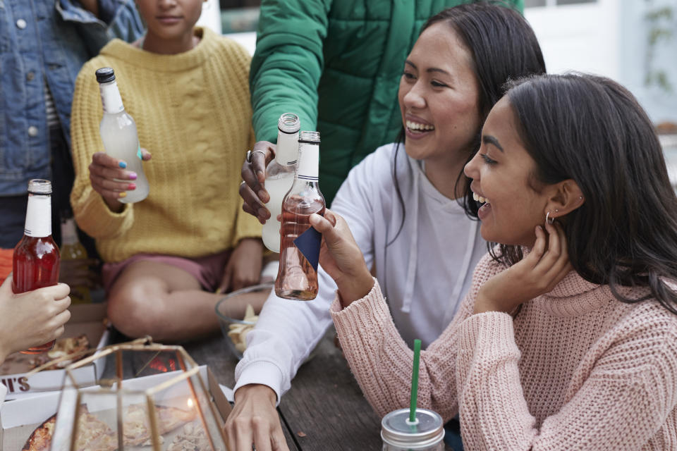 Smiling women toasting drinks with friends at table during garden party in backyard