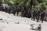 Security forces walks past debris scattered on a street after rebels from the Moro National Liberation Front (MNLF) clashed with government troops in Zamboanga city, southern Philippines September 9, 2013. Rebels took 30 civilian hostages in the southern Philippines on Monday and held security forces in a standoff as part of a drive to derail peace talks, officials said. Police commandos cordoned off parts of Zamboanga City on the island of Mindanao after a rogue faction of the Moro National Liberation Front (MNLF) took hostages and tried to march to the city hall to raise their flag, an army commander said. REUTERS/Stringer (PHILIPPINES - Tags: POLITICS MILITARY CIVIL UNREST)