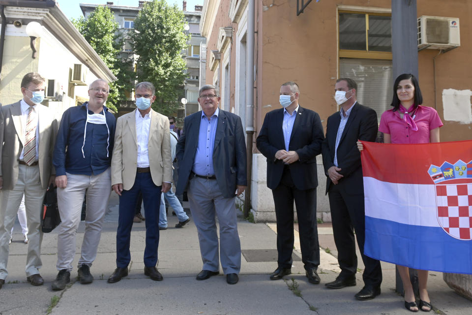 Officials including Rijeka Mayor Vojko Obersnela and Croatia's Minister of tourism Gari Capelli wait to welcome a train to arrive from the Czech Republic in Rijeka, Croatia, Wednesday, July 1, 2020. A train carrying some 500 tourists from the Czech Republic has arrived to Croatia as the country seeks to attract visitors after easing lockdown measures against the new coronavirus.(AP Photo)