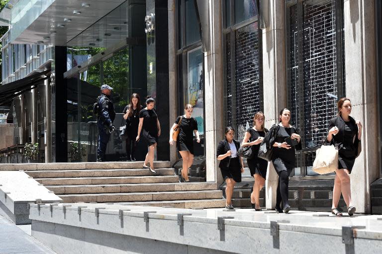 Armed police evacuate employees from the offices next to a cafe in the central business district of Sydney on December 15, 2014