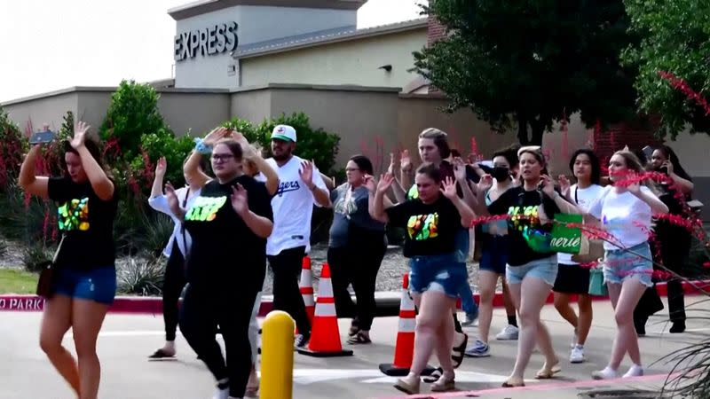 Shoppers leave with their hands up after police responded to a gunman at Allen Premium Outlets