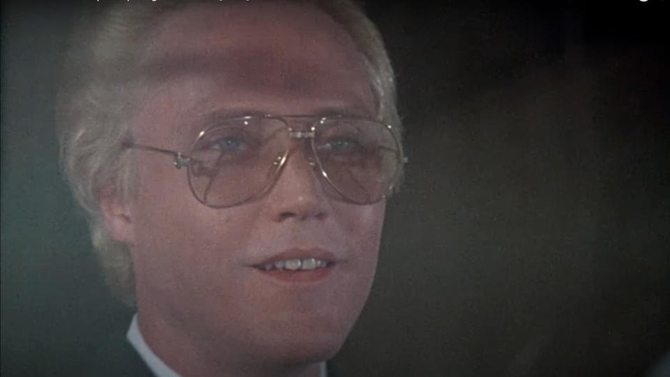 Christopher Walken smiles as he looks out a window in A View to a Kill.