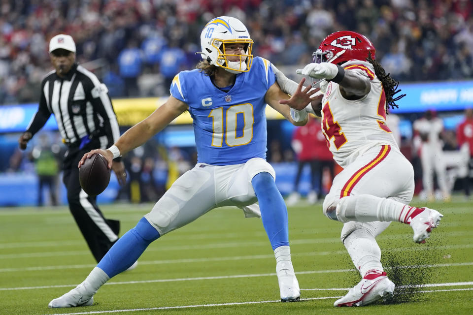Los Angeles Chargers quarterback Justin Herbert, left, looks to pass under pressure from Kansas City Chiefs outside linebacker Nick Bolton during the second half of an NFL football game Thursday, Dec. 16, 2021, in Inglewood, Calif. (AP Photo/Ashley Landis)