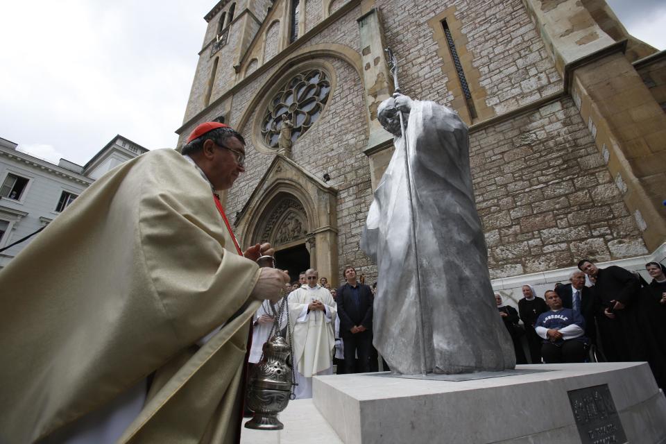 Bosnian Cardinal Vinko Puljic unveils the statue of Pope John Paul II in front of the cathedral in Sarajevo, Bosnia, on Wednesday, April 30, 2014. Thousands of Bosnians have celebrated the canonization of Pope John Paul II by unveiling a statue in the heart of Sarajevo. John Paul’s support for Sarajevo's resistance to nationalist efforts to destroy the traditional inter-cultural and inter-religious fabric of the city during the 1992-95 war made him very popular among the city's predominantly Muslim population. The crowd shouted “long live the pope” as the three meter-high statue was unveiled Wednesday in front of the cathedral. (AP Photo/Amel Emric)