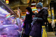 Customers wearing face masks to protect against the spread of the coronavirus shop at the Reading Terminal Market in Philadelphia, Wednesday, Feb. 16, 2022. Americans who have been clamoring for an end to mask-wearing have welcomed new guidance from the Centers for Disease Control and Prevention. It says healthy people in most areas of the country can safely stop wearing masks. But others remain wary that the pandemic could throw a new curveball. (AP Photo/Matt Rourke)