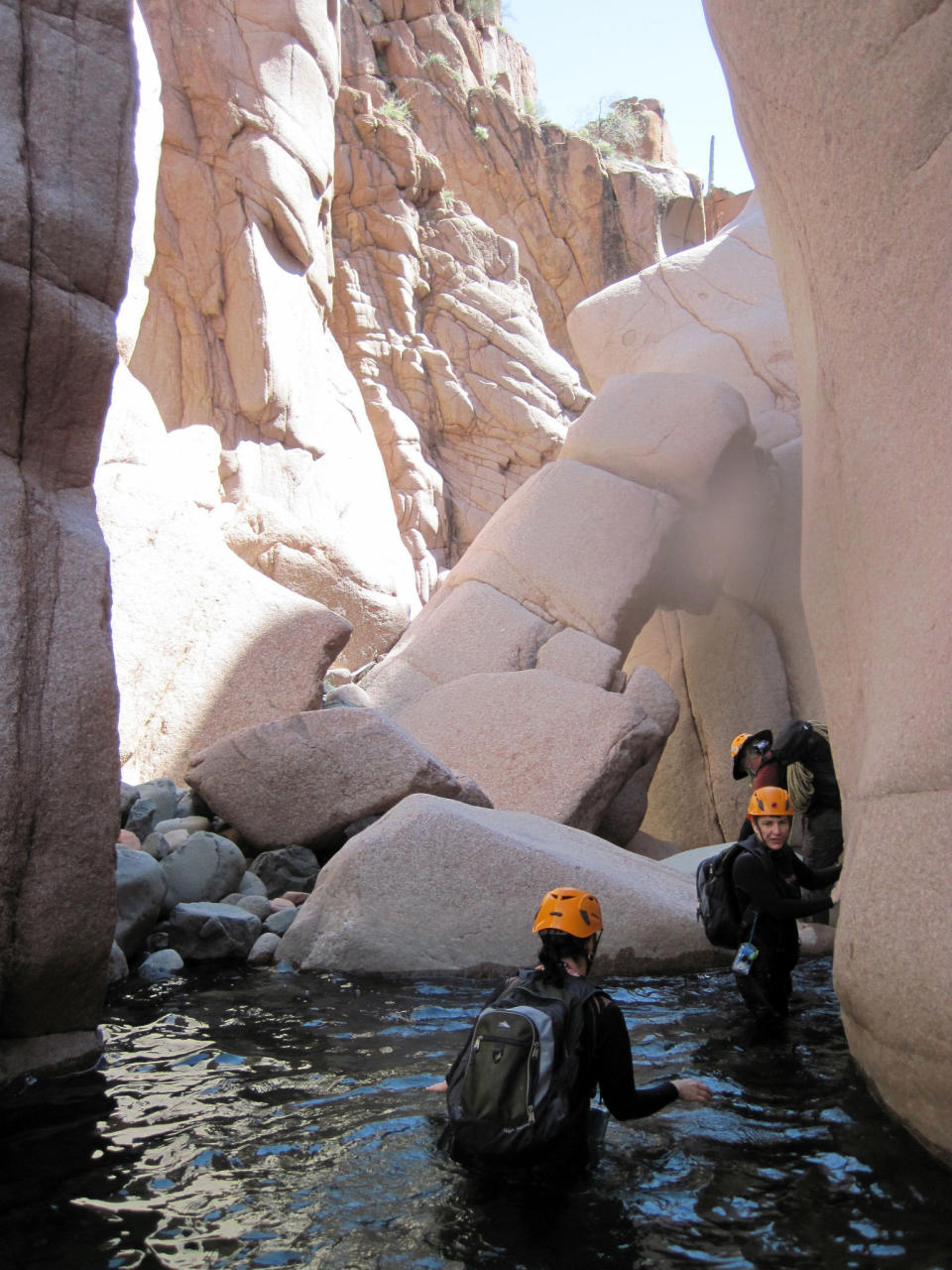 This April 19, 2012 photo provided by Charmaine Noronha shows hikers in wetsuits and helmets wading in Salome Creek in Salome Canyon, in Arizona’s Tonto National Forest. The sport of canyoneering includes hiking, climbing, sliding and wetsuit-wading but can be tackled by novices accompanied by an experienced guide. (AP Photo/Charmaine Noronha)