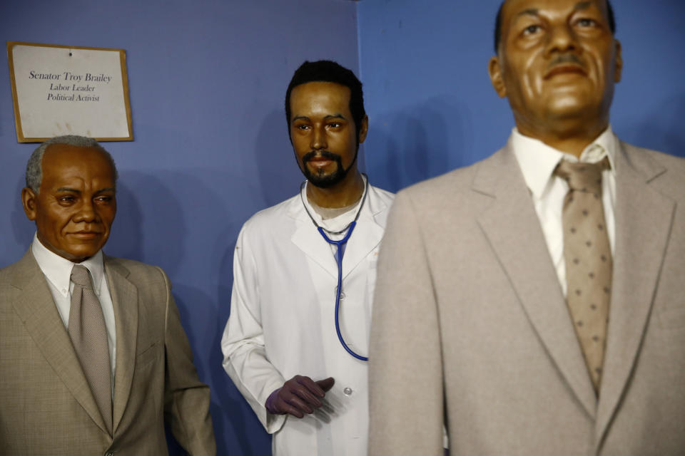 In this Aug. 15, 2018 photo, a wax figure depicting Department of Housing and Urban Development secretary Ben Carson, center, from his days as a neurosurgeon stands in a gallery at the National Great Blacks In Wax Museum in Baltimore. Carson’s story of growing up in a single-parent household and climbing out of poverty to become a world-renowned surgeon was once ubiquitous in Baltimore, where Carson made his name. But his role in the Trump Administration has added a complicated epilogue, leaving many who admired him feeling betrayed, unable to separate him from the politics of a president widely rejected by African Americans here. (AP Photo/Patrick Semansky)