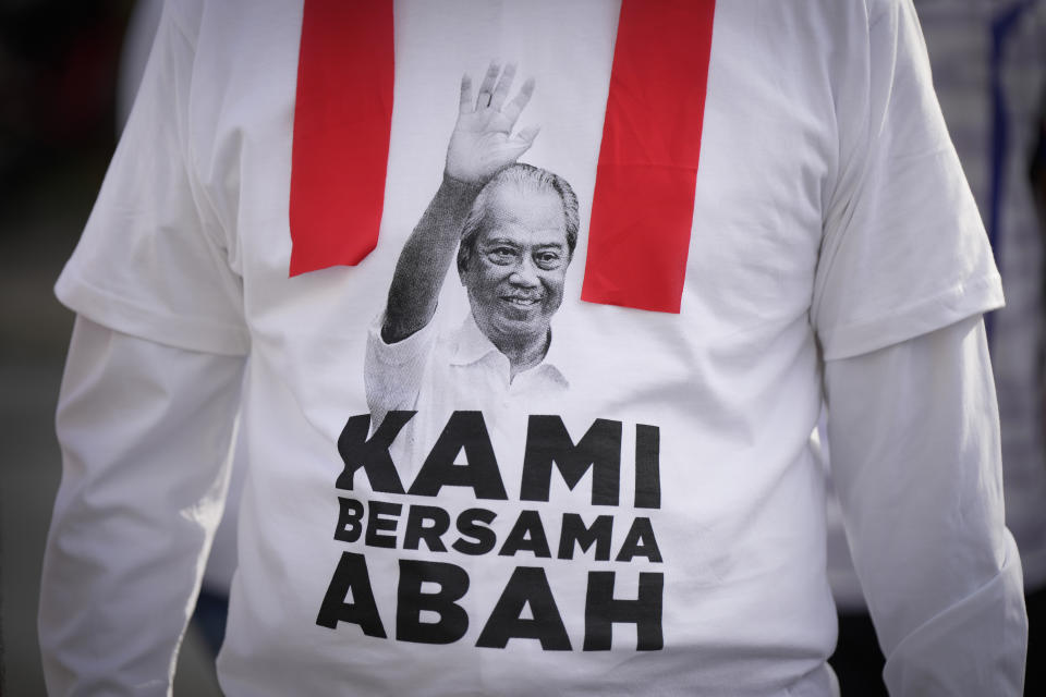 A supporter wears a T-shirt with Malaysia's former Prime Minister Muhyiddin Yassin picture to show support outside courthouse where he appeared on his corruption charges in Kuala Lumpur, Malaysia, Friday, March 10, 2023. Muhyiddin, who led Malaysia from March 2020 until August 2021, will be the country's second leader to be indicted after leaving office. Banner read "we are with you Abah (nick name of Muhyuddin" (AP Photo/Vincent Thian)