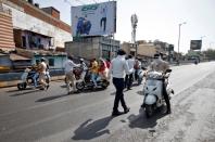 Policemen stop people travelling on scooters after the lockdown by Gujarat state government to limit the spreading of coronavirus disease (COVID-19), in Ahmedabad