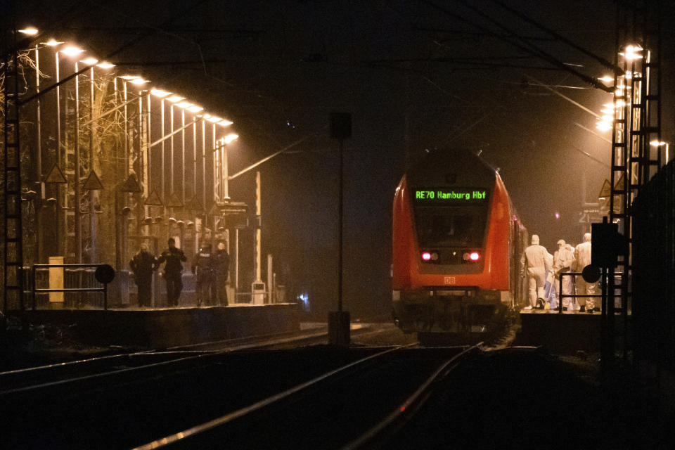 Forensics staff are on duty on a platform at a regional train, with police officers standing opposite, at Brokstedt station in Brockstedt, Germany, Wednesday, Jan. 25, 2023. A man stabbed and wounded several people on a train in northern Germany on Wednesday before police detained him, and two of the victims died, German news agency dpa reported. (Jonas Walzberg/dpa via AP)