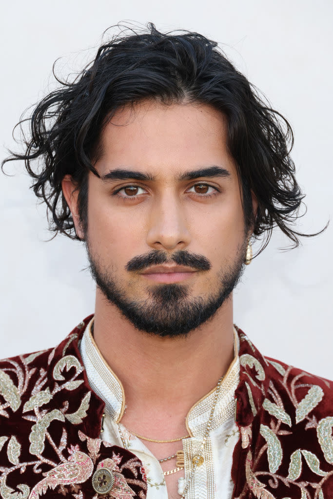 Avan Jogia in an ornate jacket with gold embroidery and a white shirt, poses for a portrait