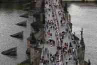 FILE - In this Tuesday, June 30, 2020 file photo, residents sit to dine on a 500 meter long table set on the medieval Charles Bridge, after restrictions were eased following the coronavirus pandemic in Prague, Czech Republic. Weeks after the citizens of Prague said a symbolic farewell to the coronavirus, the second wave has struck hard and the number of confirmed cases is setting new records almost daily. It is currently at a similar level to its neighbor German, which has a population eight times the size. The health minister has announced new restrictions, including closing bars, restaurants and clubs at midnight and making it mandatory to wear masks in all spaces in schools. (AP Photo/Petr David Josek, File)