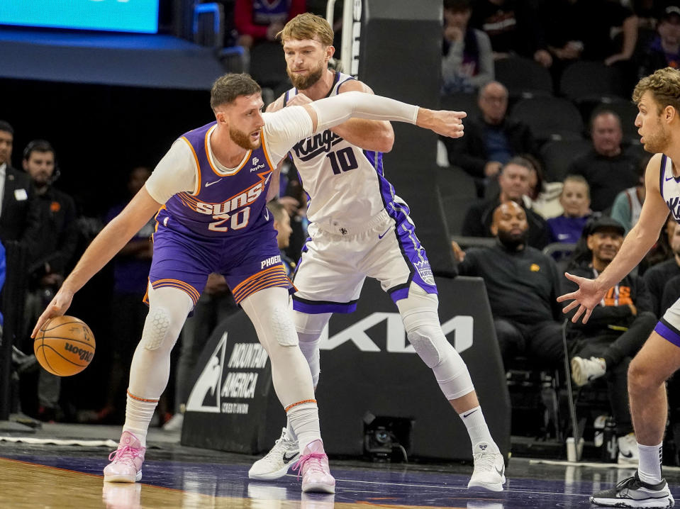 Phoenix Suns' Just Nurkic (20) keeps the ball away from Sacramento Kings' Domantas Sabonis (10) during the first half of an NBA basketball game Friday, Dec. 8, 2023 in Phoenix. (AP Photo/Darryl Webb)