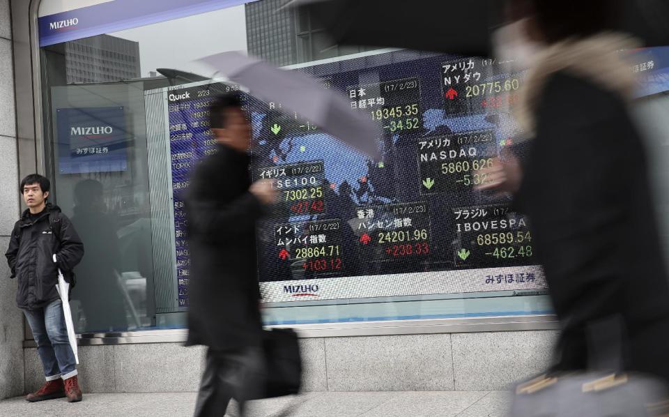 People walk past an electronic stock indicator of a securities firm in Tokyo, Thursday, Feb. 23, 2017. Asian shares slipped Thursday after the latest Fed minutes raised the possibility that a U.S. rate hike could come sooner than expected. (AP Photo/Shizuo Kambayashi)