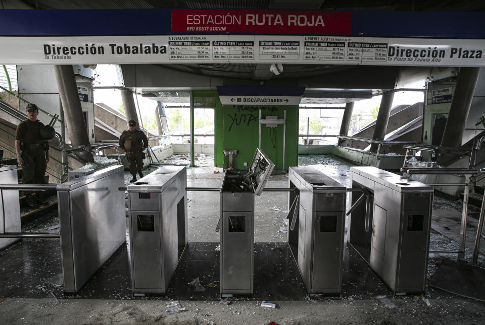 Chilean police stand in a subway station that was damaged during last night's protests, in Santiago, Chile, Saturday, Oct. 19, 2019. The protests started on Friday afternoon when high school students flooded subway stations, jumping turnstiles, dodging fares and vandalizing stations as part of protests against a fare hike, but by nightfall had extended throughout Santiago with students setting up barricades and fires at the entrances to subway stations, forcing President Sebastian Pinera to announce a state of emergency and deploy the armed forces into the streets. (Photo: Esteban Felix/AP)