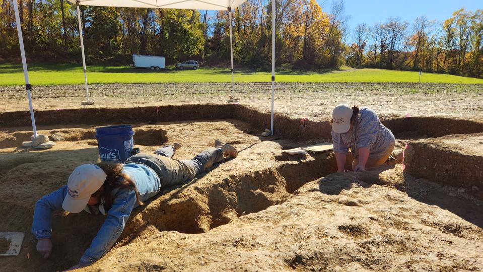 In this photo provided by John Crawmer, Jane C. Skinner and Samantha Muscella excavate post holes at the bottom of a stockade trench, Thursday, Oct. 27, 2022, in York, Pa. Researchers say they have solved a decades-old riddle by finding remnants of the stockade and therefore the site of a prison camp in York, that housed British soldiers for nearly two years during the American Revolutionary War. (John Crawmer via AP)