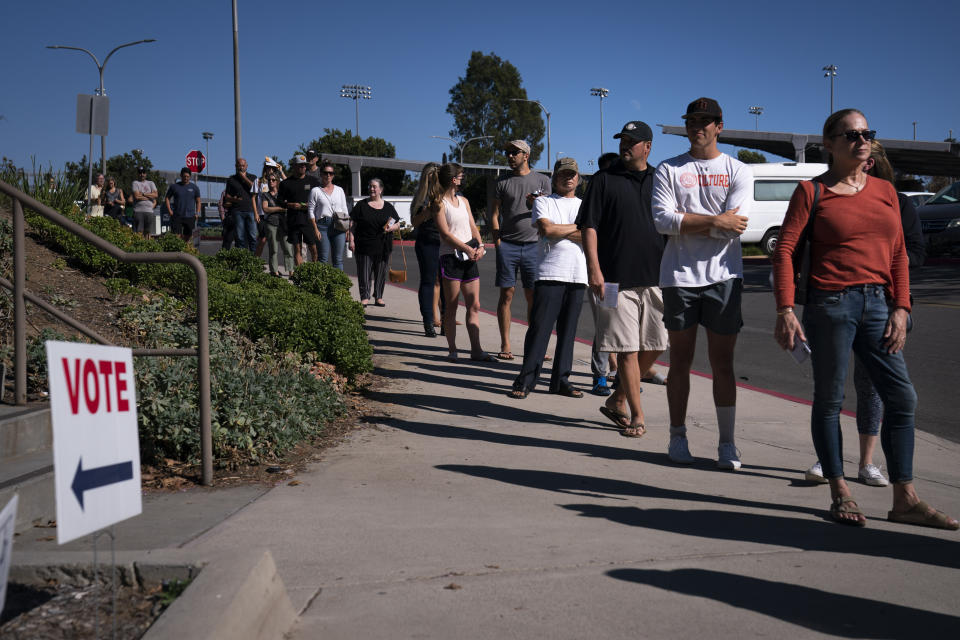 FILE - In this Sept. 14, 2021, file photo, people wait in line outside a voting center to cast their recall ballots in Huntington Beach, Calif. Every registered California voter will get a ballot mailed to them in future elections under a bill signed Monday, Sept. 27, 2021, by Democratic Gov. Gavin Newsom. The nation's most populous state mailed everyone a ballot in the two most recent elections due to concerns about voting during the pandemic. Newsom's signature makes that change permanent. Even prior to the pandemic, most Californians were receiving ballots in the mail. (AP Photo/Jae C. Hong, File)