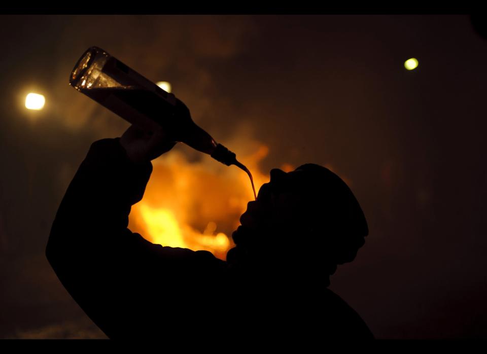 A man drinks near a bonfire in San Bartolome de Pinares, Spain, Monday, Jan. 16, 2012, in honor of Saint Anthony, the patron saint of animals. On the eve of Saint Anthony's Day, hundreds drink and ride their horses trough the narrow cobblestone streets of the small village of San Bartolome during the "Luminarias," a tradition that dates back 500 years and is meant to purify the animals with the smoke of the bonfires and protect them for the year to come. (Daniel Ochoa de Olza, AP)