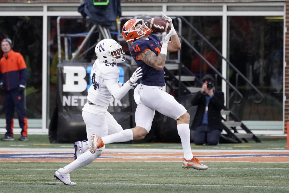 Illinois wide receiver Casey Washington (14) catches a deep pass from Brandon Peters as Northwestern defensive back Rod Heard II defends during the first half of an NCAA college football game Saturday, Nov. 27, 2021, in Champaign, Ill. (AP Photo/Charles Rex Arbogast)