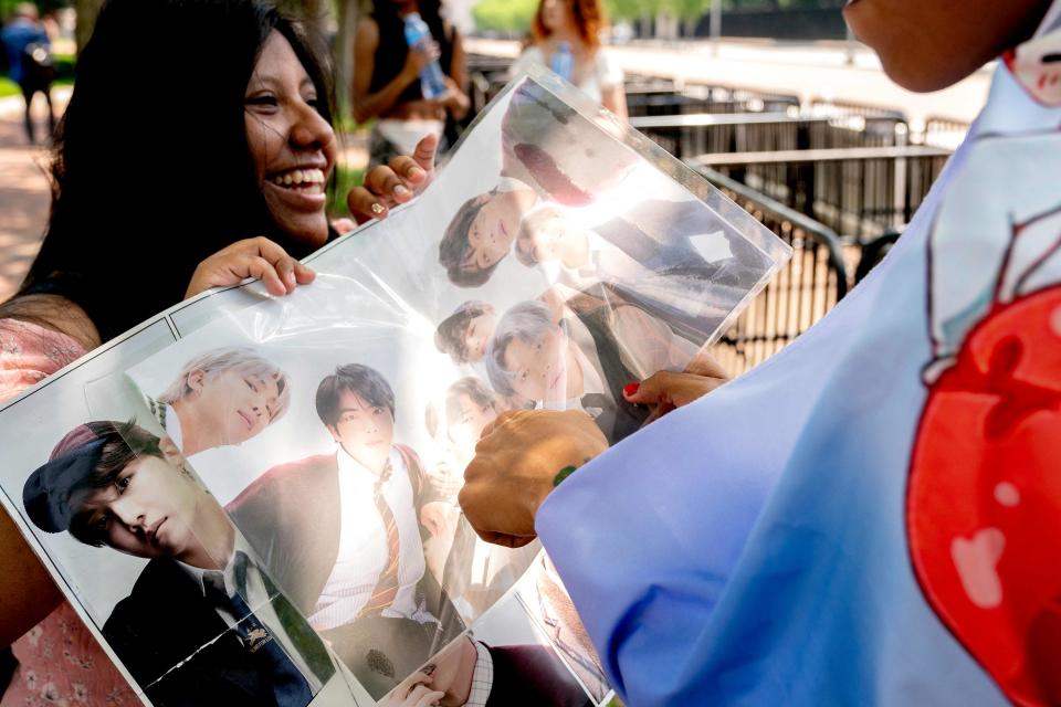 A fan of BTS holds up a poster of the boy band outside the White House.
