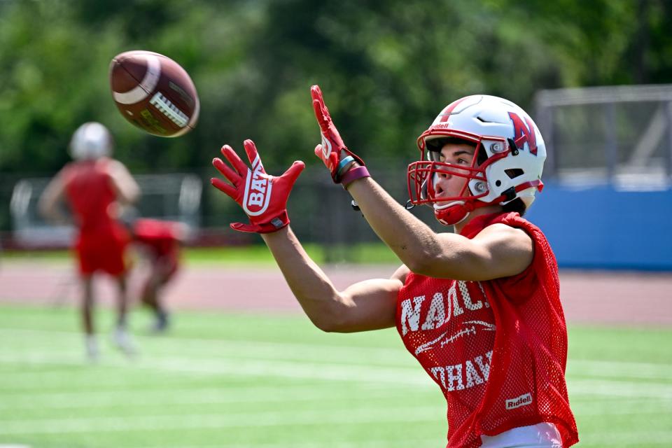 Natick High School football player Charlie Lewis keeps his focus as he catches this pass during the first day of practice at Memorial Field, Friday, Aug. 8, 2023.