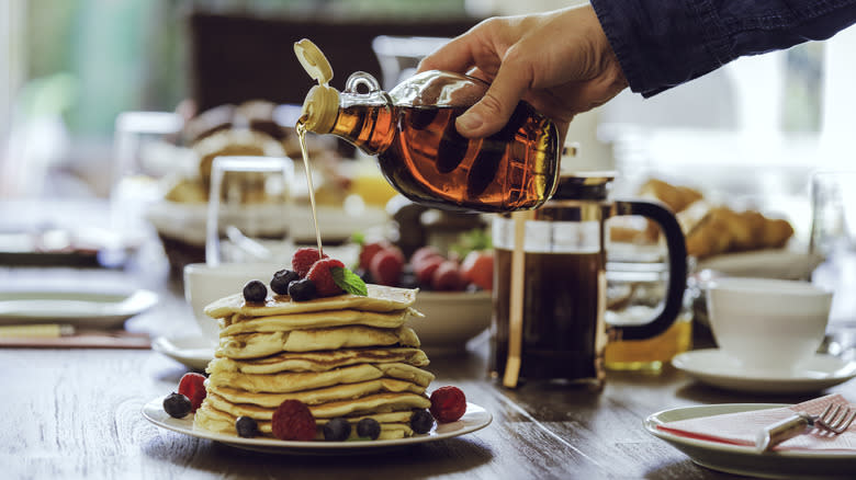 Pouring maple syrup over pancakes