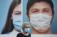 A woman wearing a protective face mask walks by a billboard raising awareness of wearing face masks and washing hands following government measures to help stop the spread of the coronavirus, in Ramat Gan, near Tel Aviv, Israel, Thursday, July 16, 2020. Israel reached a new daily record of confirmed coronavirus cases on Thursday as the government discussed renewed lockdown measures to contain the growing outbreak. (AP Photo/Oded Balilty)