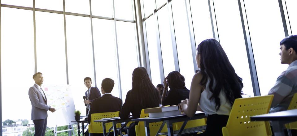 Group of attentive adult students with speaker giving a talk or trainer in classroom or seminar at business training to success of target.