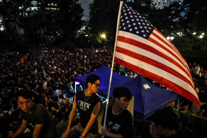 Hong Kongers opposed to an extradition bill with mainland China hold an American flag at an August 2019 protest (AFP Photo/Lillian SUWANRUMPHA)