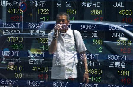 A man looks at stock prices displayed at a board showing market indices in Tokyo July 28, 2015. REUTERS/Thomas Peter