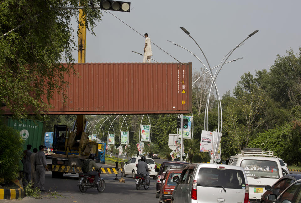 Pakistani authorities place shipping containers at the entrance of diplomatic enclave in Islamabad, Pakistan, Thursday, Aug. 30, 2018. Hard-line Islamists who started a march toward Pakistan's capital to protest a far-right Dutch lawmaker's plans to hold a Prophet Muhammad cartoon contest have been stopped by police. (AP Photo/B.K. Bangash)