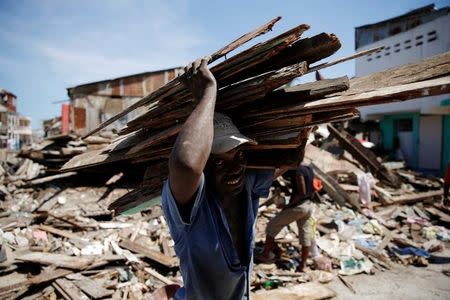 A man carries wooden planks after Hurricane Matthew passes in Jeremie, Haiti, October 8, 2016. REUTERS/Carlos Garcia Rawlins