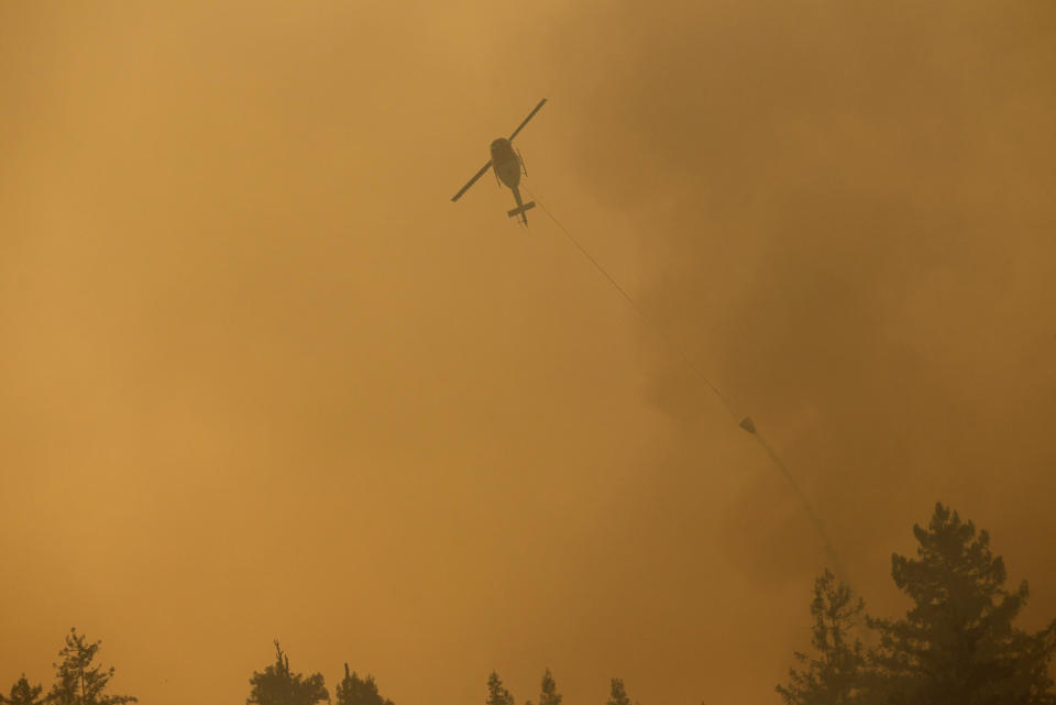 A helicopter drops ocean water on a wildfire burning on Pfeiffer Ridge in Big Sur
