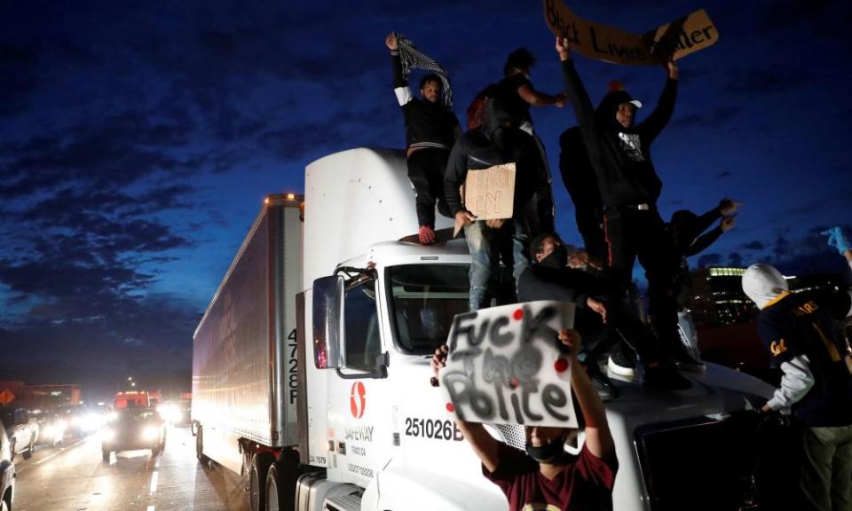 Demonstrators hold signs while standing on top of a semi-trailer on Interstate 880 during a protest against the death of African-American man George Floyd under Minneapolis police custody, in Oakland, California, U.S. May 29, 2020.