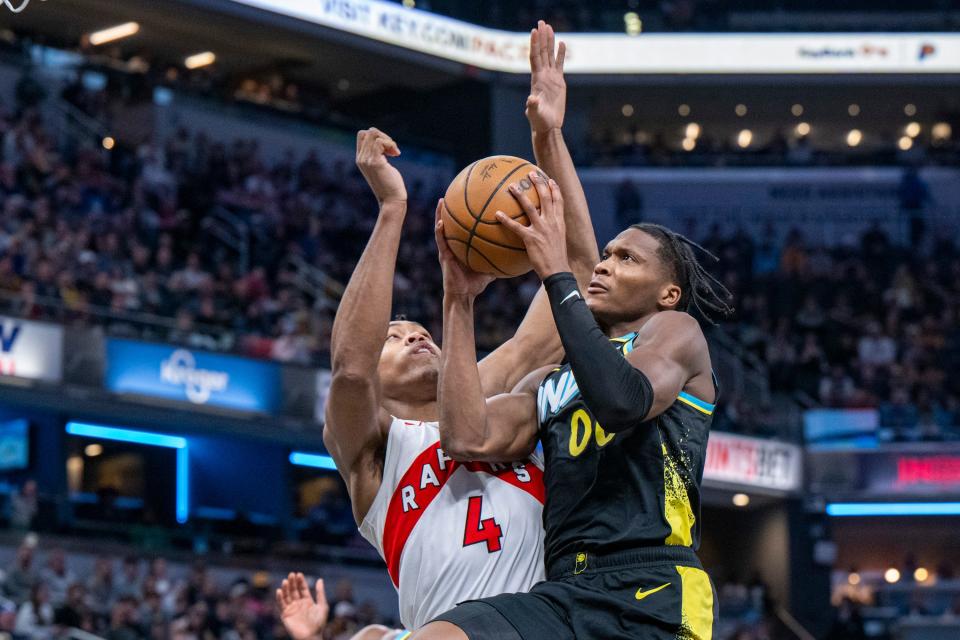 Indiana Pacers guard Bennedict Mathurin (00) makes contact with Toronto Raptors forward Scottie Barnes (4) en route to the basket during the first half of an NBA basketball game in Indianapolis, Monday, Feb. 26, 2024. (AP Photo/Doug McSchooler)