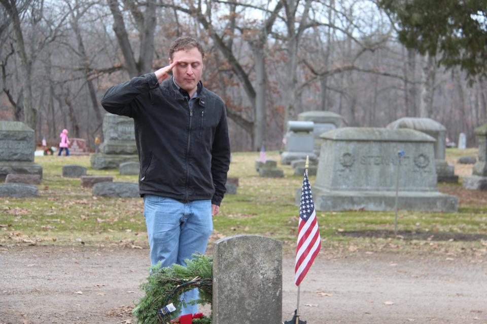 TJ Korotzer, a U.S. Marine veteran, renders a salute after placing a wreath on a veteran's grave at Oak Grove Cemetery Saturday.