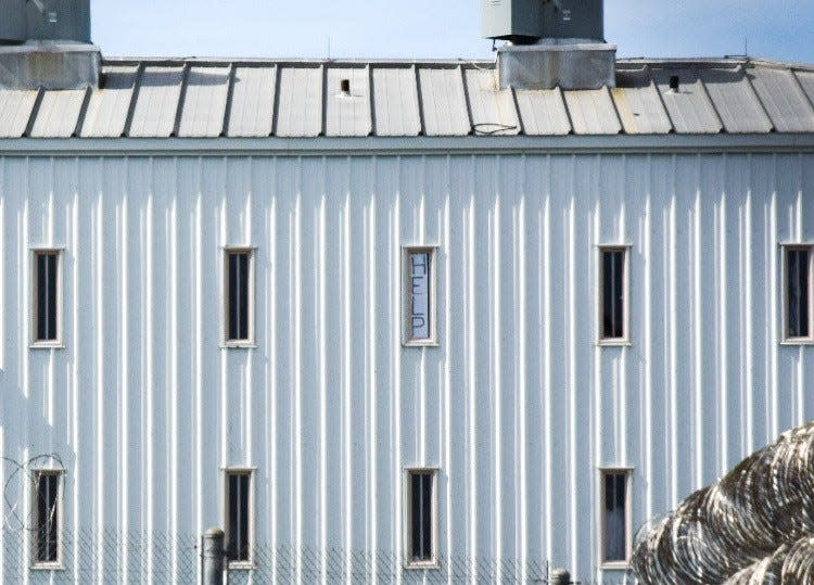 A sign saying "Help" is seen in a window at Holman Correctional Facility on Oct. 22, 2019. DOC Commissioner Jeff Dunn brought members of a prison group on a tour of the facility.